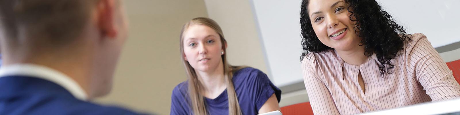 Student discussion in conference room, girl in background in focus